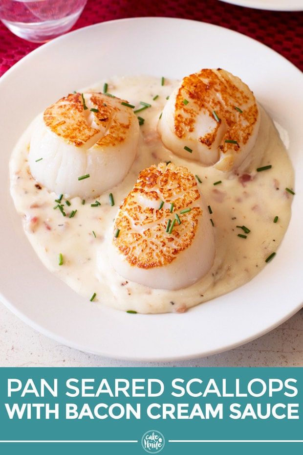 three scallops with bacon cream sauce on a white plate