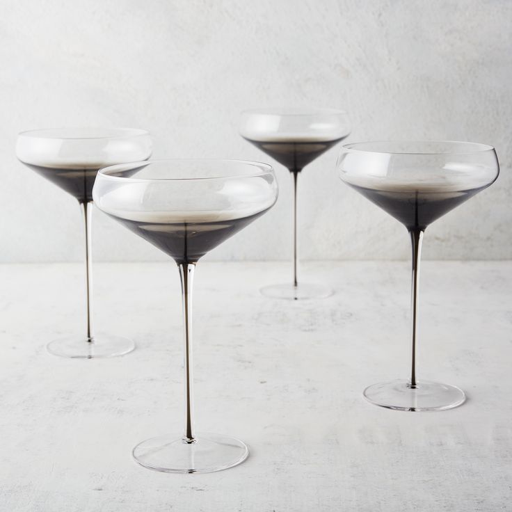 three martini glasses sitting on top of each other in front of a white wall and floor