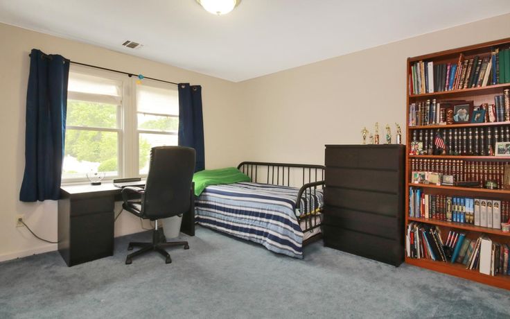 a bedroom with a bed, desk and bookshelf