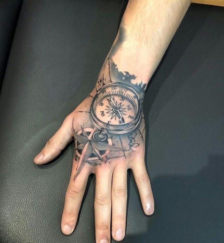 a man's hand with a compass tattoo on it