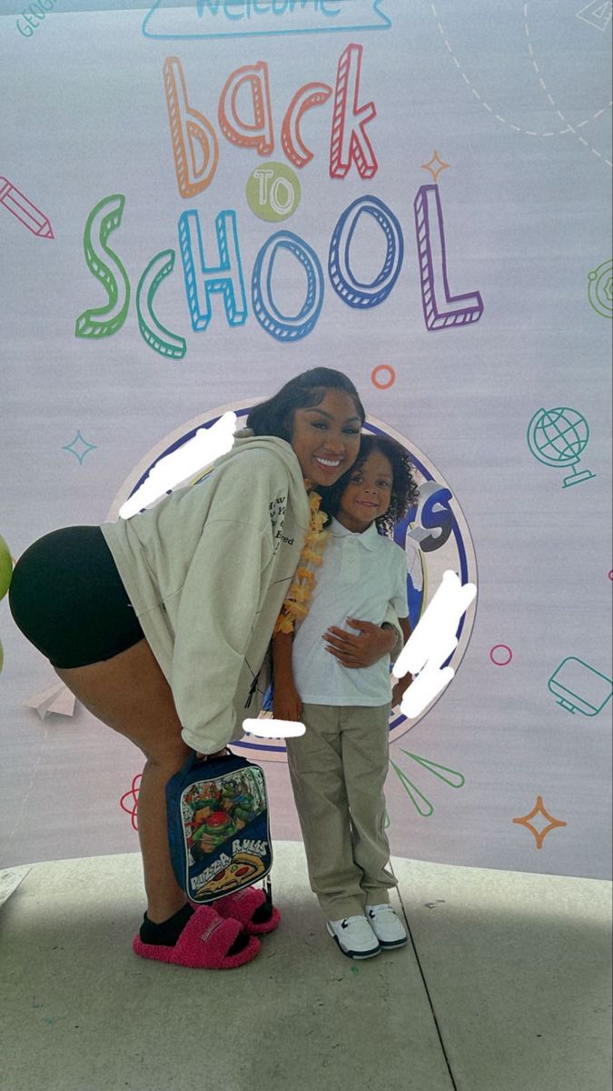 a woman standing next to a child in front of a back to school sign