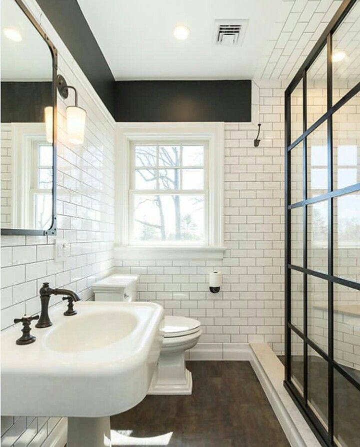 a white bathroom with black accents and wood flooring