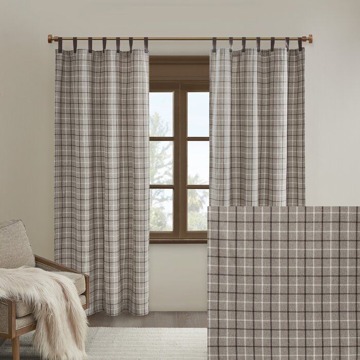 a living room with plaid curtains and a chair in front of a window that has a fur rug on the floor