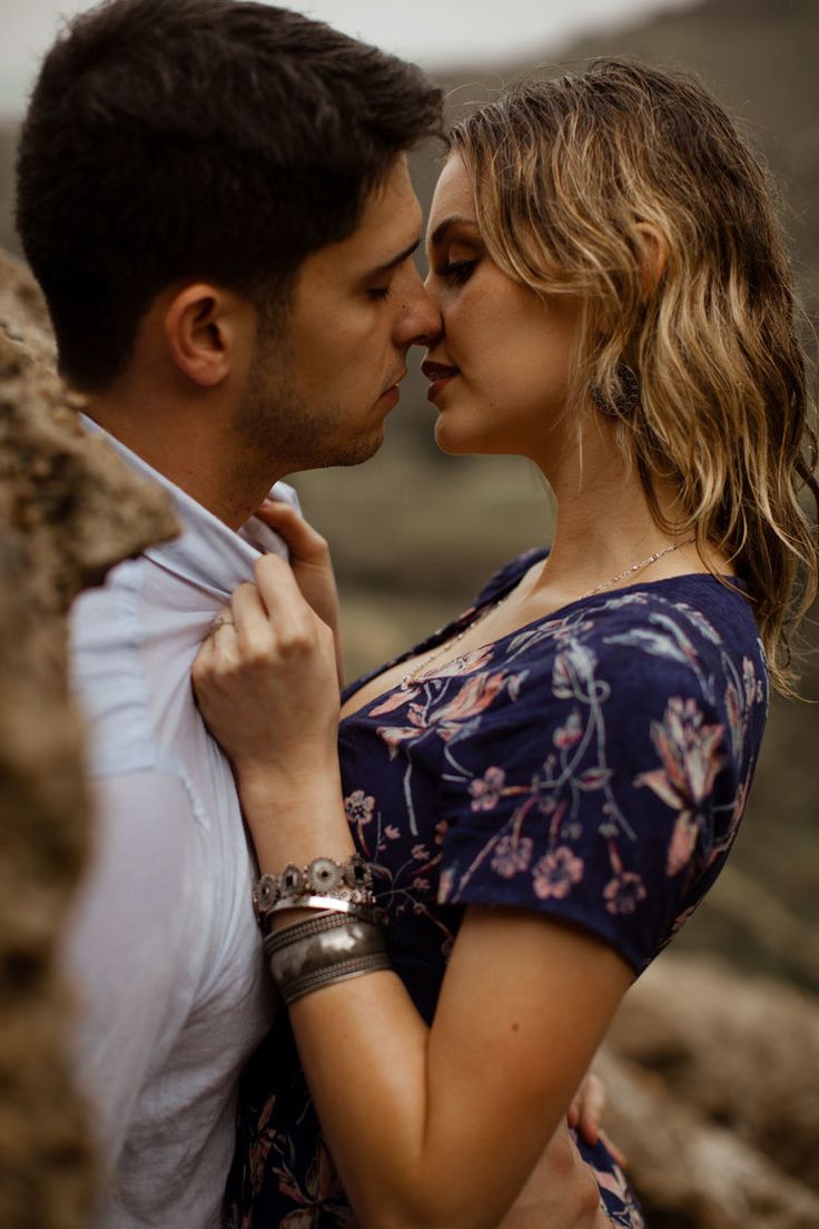 a man and woman standing next to each other with their arms around each other as they kiss