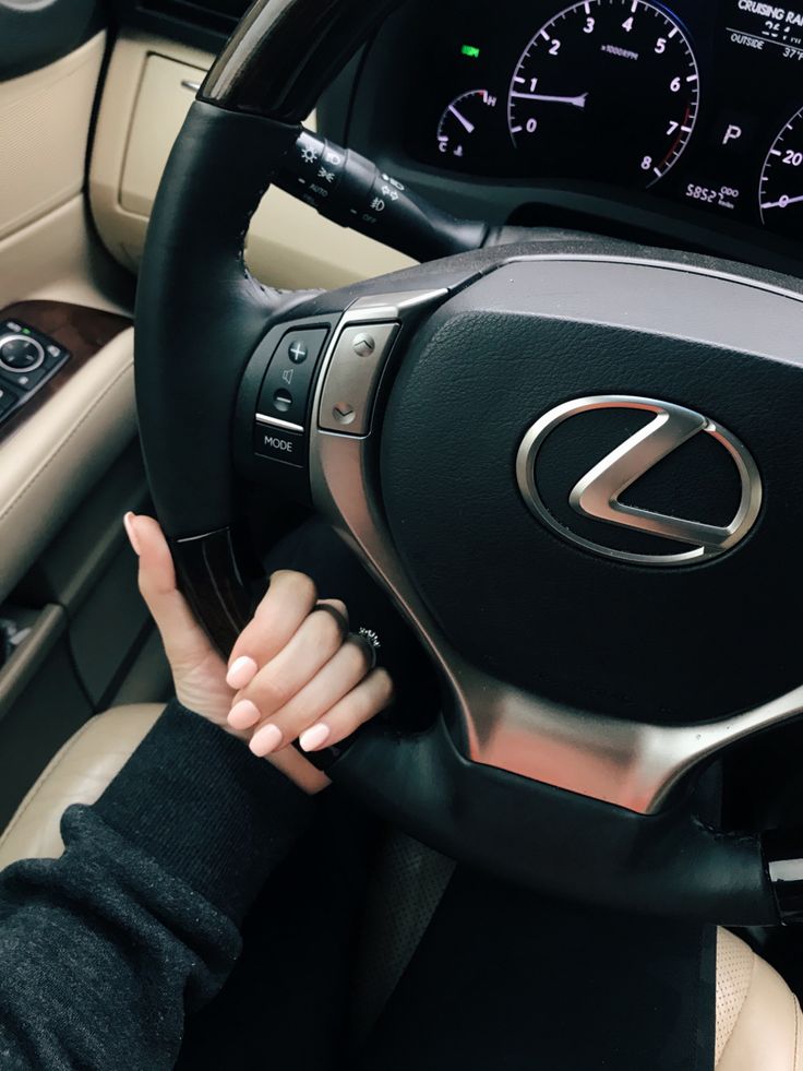 a woman is holding the steering wheel of a car with her hand on the dashboard