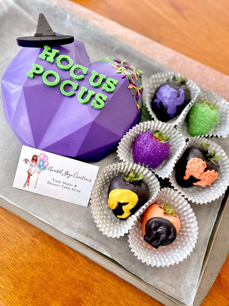 there are many halloween candies in the tray on the table with a sign that says hoccus pocus