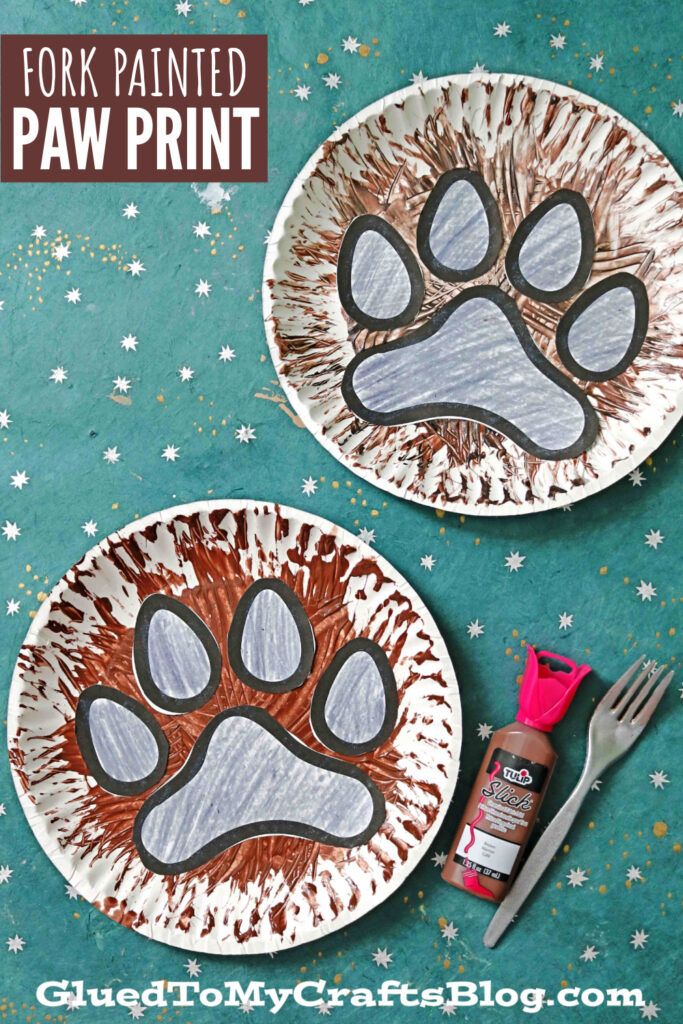 two paper plates with paw prints on them, one has a fork and the other has a bottle of paint