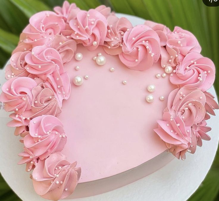 a heart shaped cake decorated with pink flowers and pearls