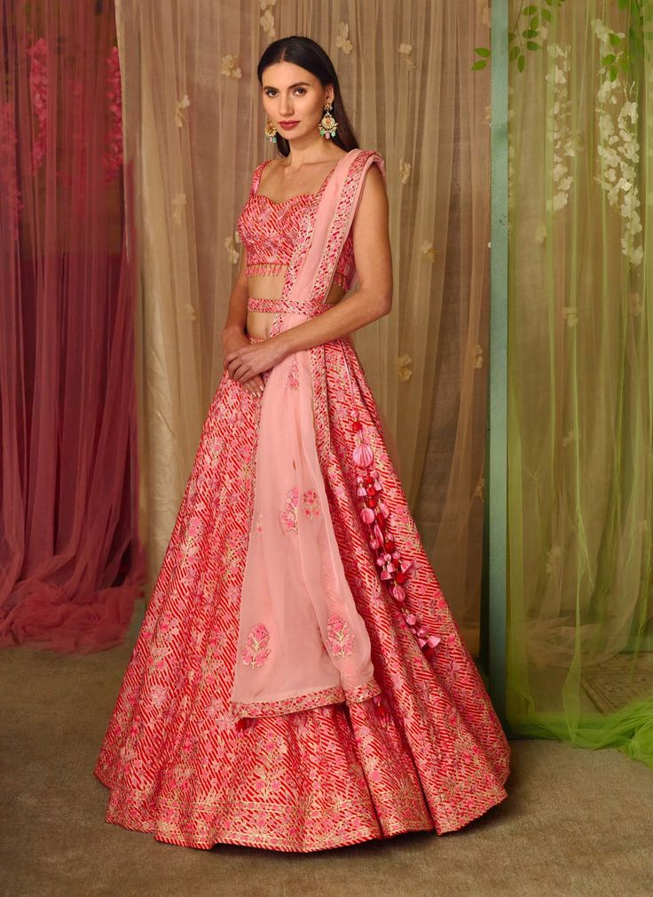 Editor's Note This set features a lehenga with thread and gota embroidered on printed silk with belt and embroidered organza dupatta Color: Pink Fabric: Silk, organza Sleeve: Sleeveless Neckline: Sweetheart Embroidery details: Gota and thread embroidery Component: Blouse, lehenga, belt and dupatta Lehenga length: 43" inches and blouse: 14" inches Occasion: Sangeet Care: Dry clean only About the Designer Shyam Narayan Prasad started his journey in the Indian Fashion Design Industry with a couture Pink Silk Sharara With Floral Embroidery, Pink Raw Silk Set With Floral Embroidery, Pink Organza Sets For Navratri, Pink Organza Lehenga For Navratri, Pink Organza Lehenga With Zari Work, Pink Organza Choli For Navratri, Pink Bollywood Sets In Organza, Pink Sharara With Floral Embroidery In Tissue Silk, Pink Tissue Silk Sharara With Floral Embroidery