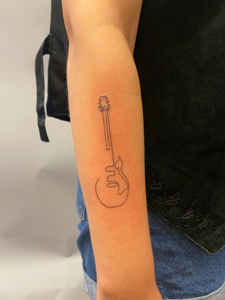 a person with a guitar tattoo on their arm