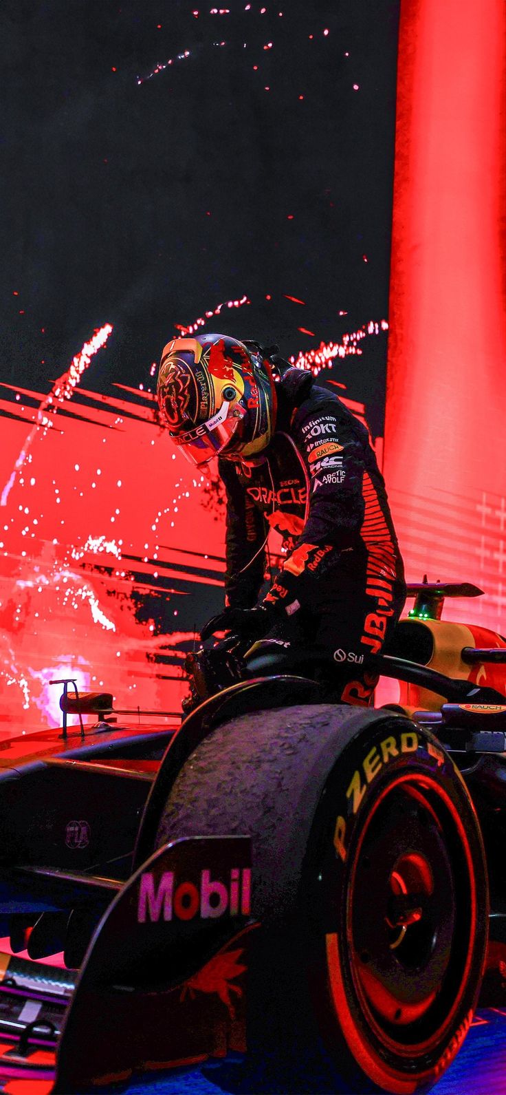 a man standing on top of a racing car in front of a red light display