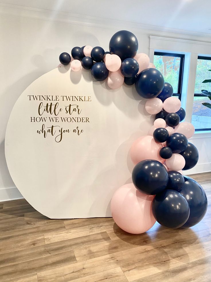 a balloon arch with black, pink and white balloons