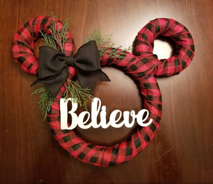 a red and black wreath with the word believe written on it next to a minnie mouse head