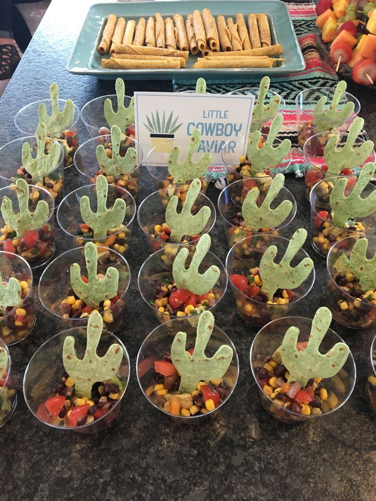 small plastic cups filled with different types of food and cactus decorations on top of them