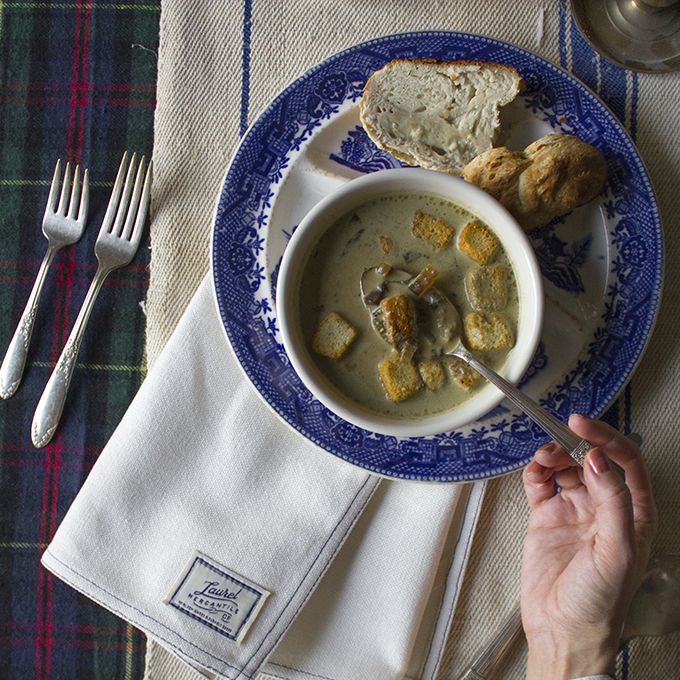 a bowl of soup on a blue and white plate with silverware next to it