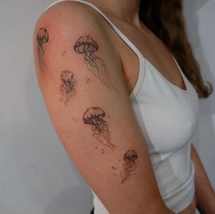 a woman's arm with jellyfish tattoos on it