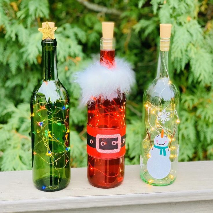 three wine bottles decorated with christmas decorations