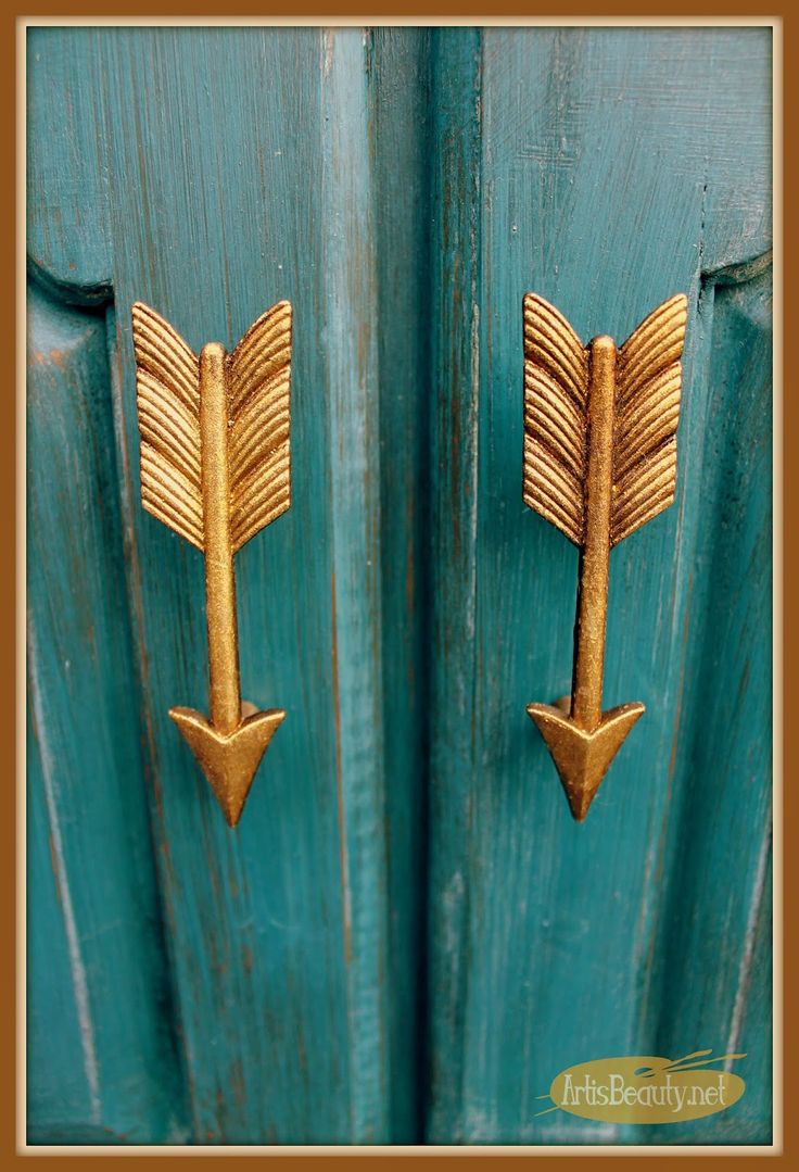 two gold arrows on the side of a blue door with wood grain inlays