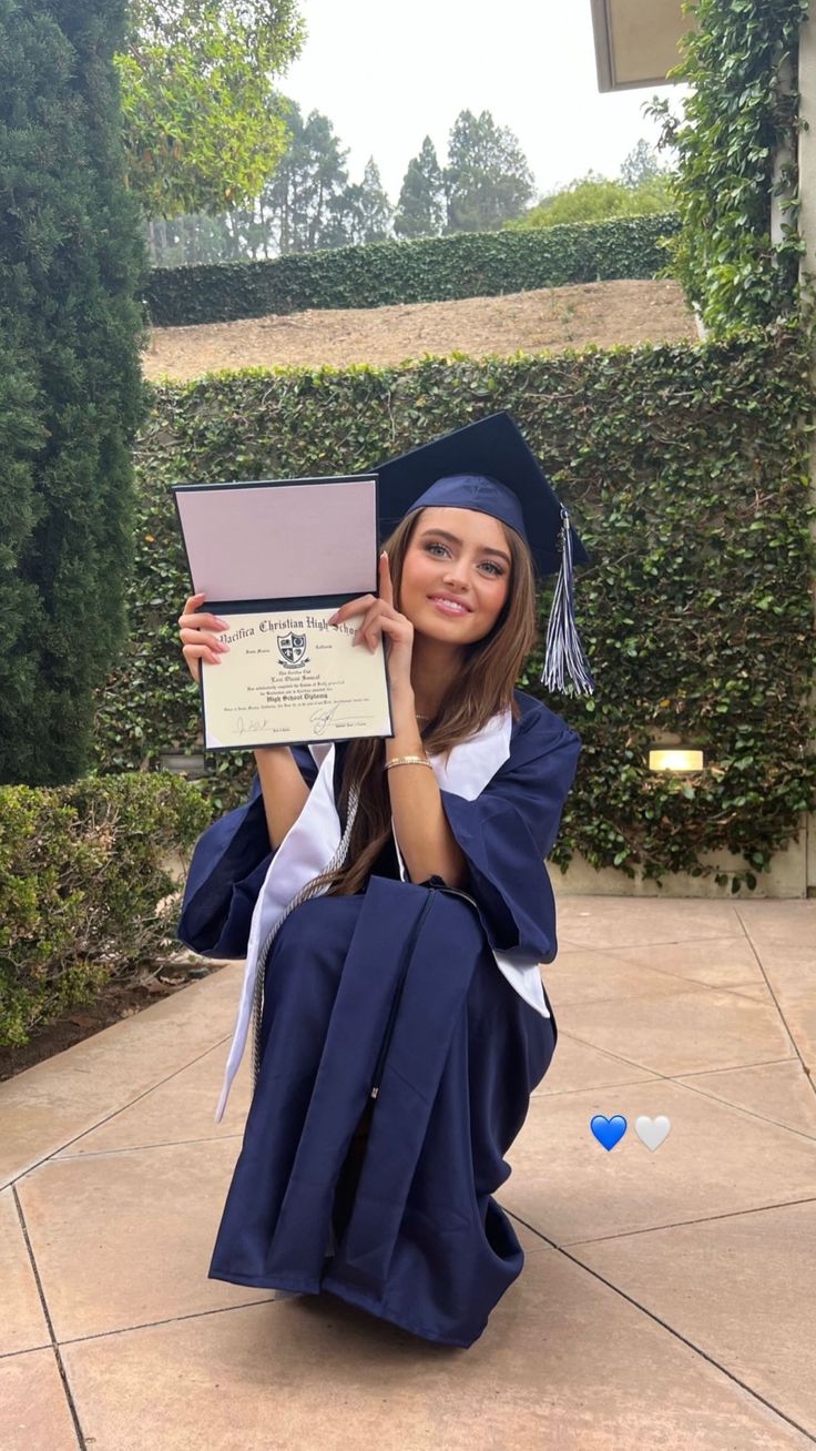 a woman sitting on the ground with her diploma