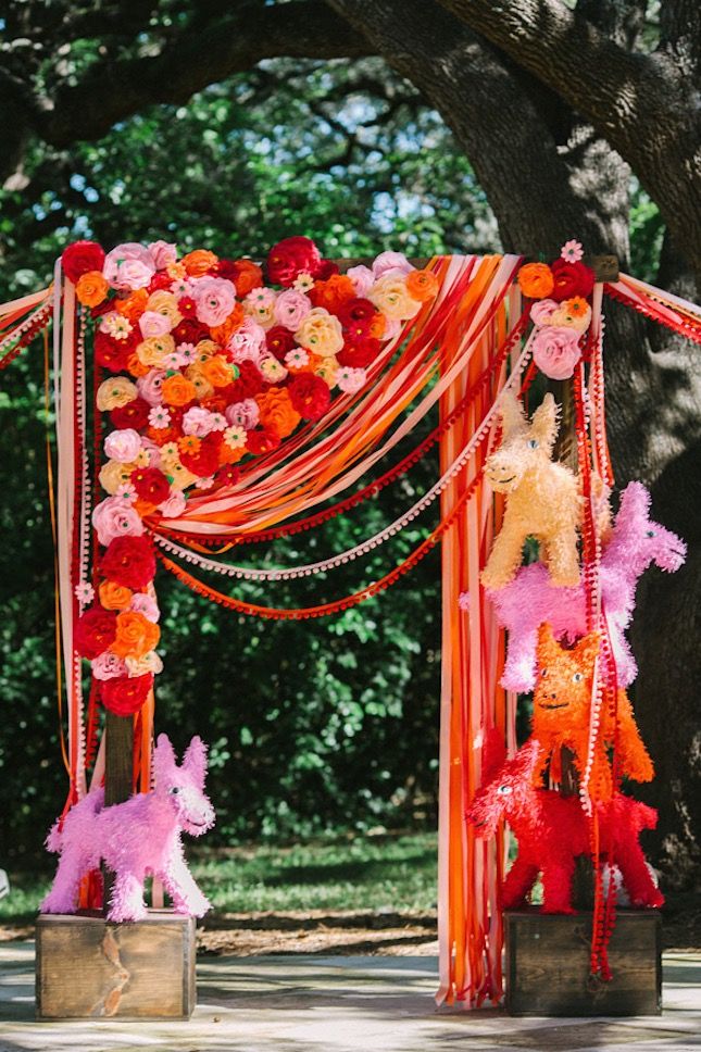 an orange and pink wedding arch decorated with poodles