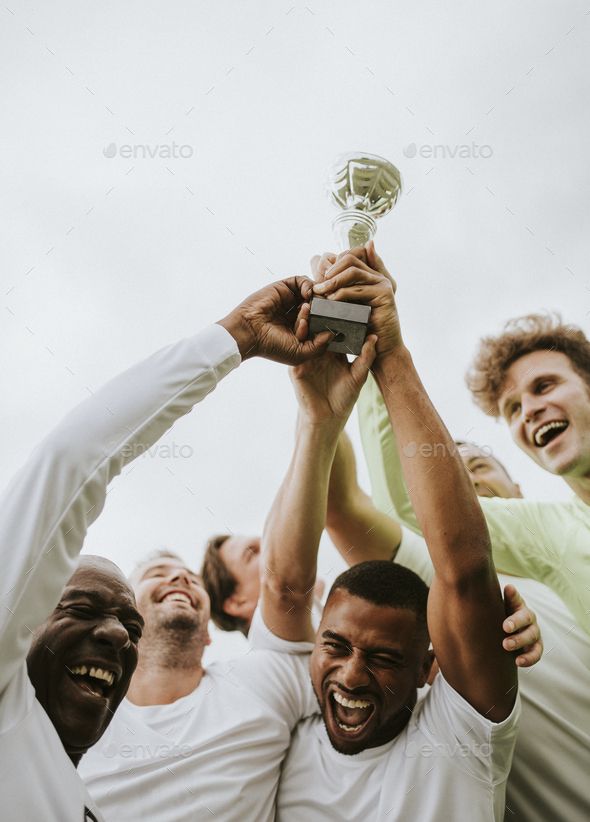 group of men holding up a trophy in the air with their hands on top of each other