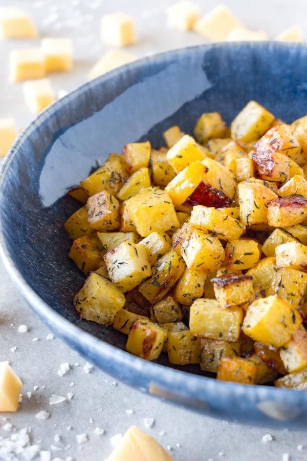 a blue bowl filled with cooked potatoes and parmesan cheese cubes on the side