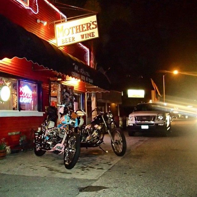 two motorcycles parked in front of a bar at night