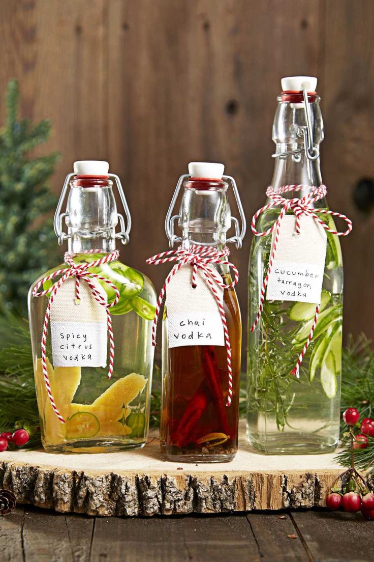 three glass bottles filled with liquid sitting on top of a wooden table next to christmas decorations