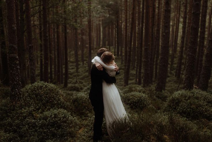 a bride and groom embracing in the woods