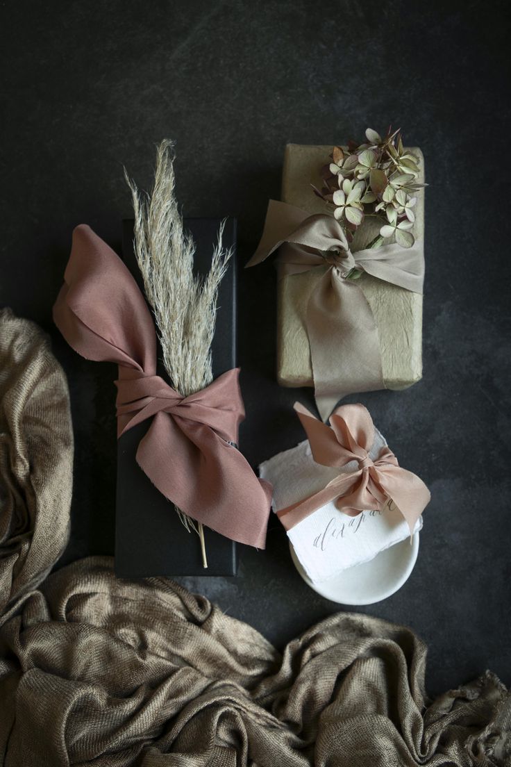 three wrapped gifts on top of a table next to a blanket and flower vases