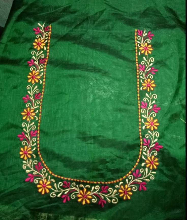 an embroidered green cloth with colorful flowers and beads on the border is sitting on a table