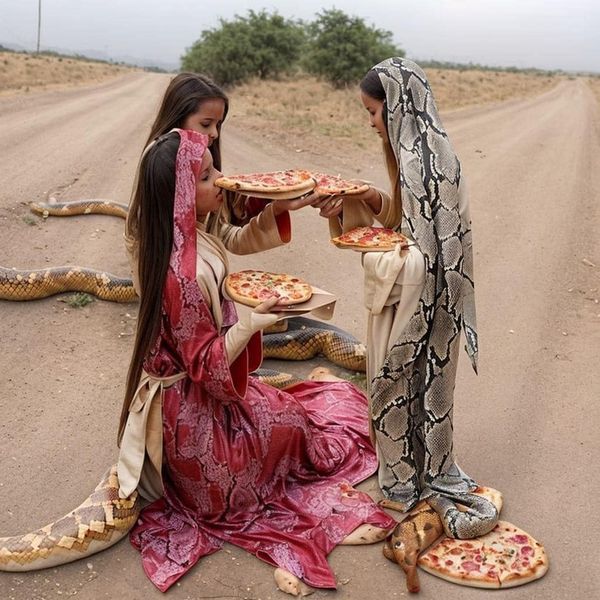 two women sitting in the middle of a desert with pizzas on their laps and snakes crawling around them