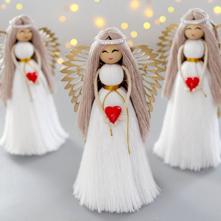 three angel figurines with hearts in their hands