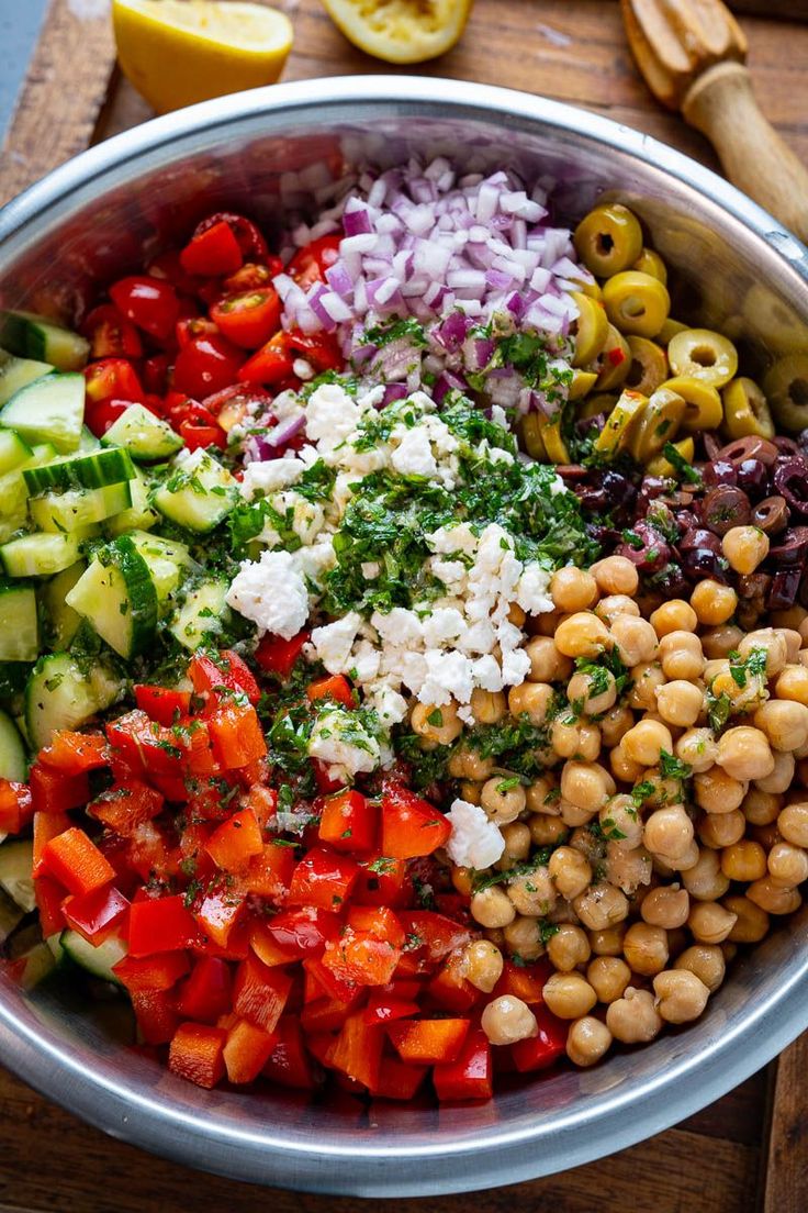 a bowl filled with vegetables and chickpeas on top of a wooden cutting board