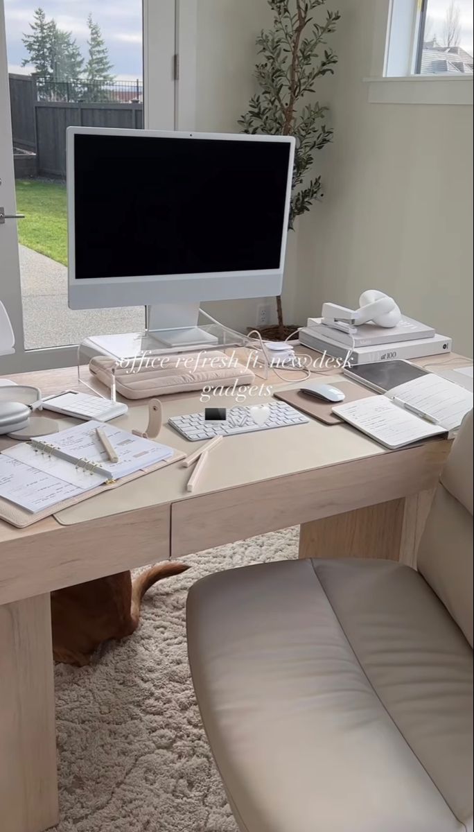 a desk with a computer monitor, keyboard and mouse on it in front of a window