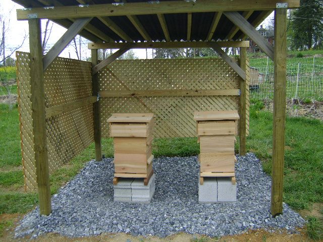 two wooden benches sitting under a pergolated area with gravel and rocks on the ground