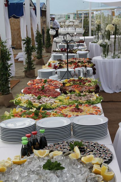 a buffet table filled with lots of food and plates on top of each other,