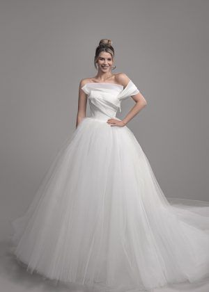 a woman in a white wedding dress posing for the camera with her hands on her hips