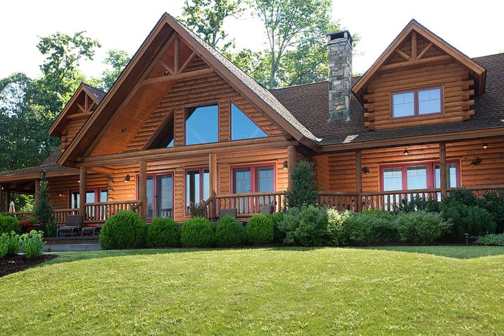 a large log home with lots of windows and wood trimmings on the front