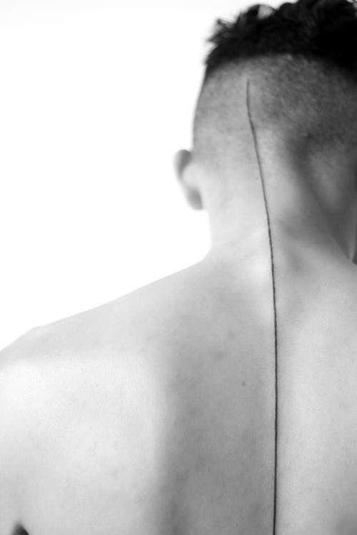 the back of a man's neck with an arrow tattoo on it