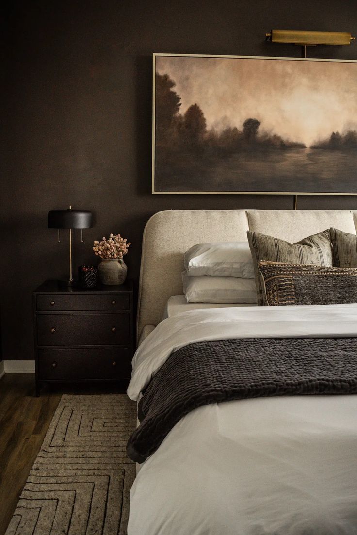 a bed with white sheets and pillows in a bedroom next to a painting on the wall