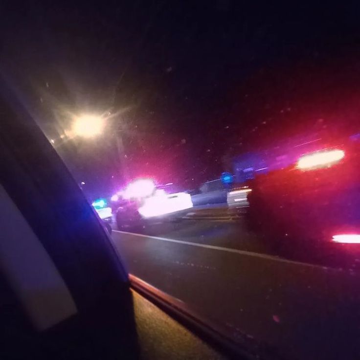 two police cars driving down the road at night