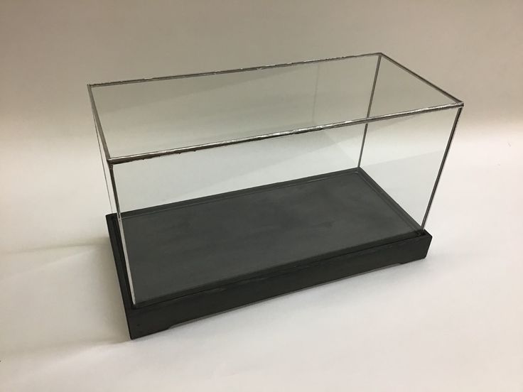 an empty glass display case sitting on top of a white table with a black base