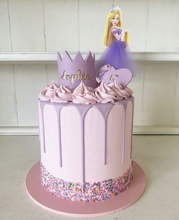 a princess cake with pink frosting and sprinkles on the bottom tier