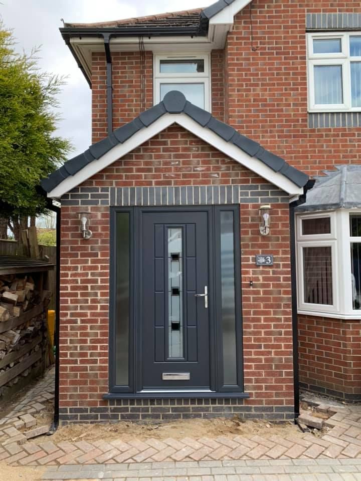 a brick house with a black front door and side windows on either side of it