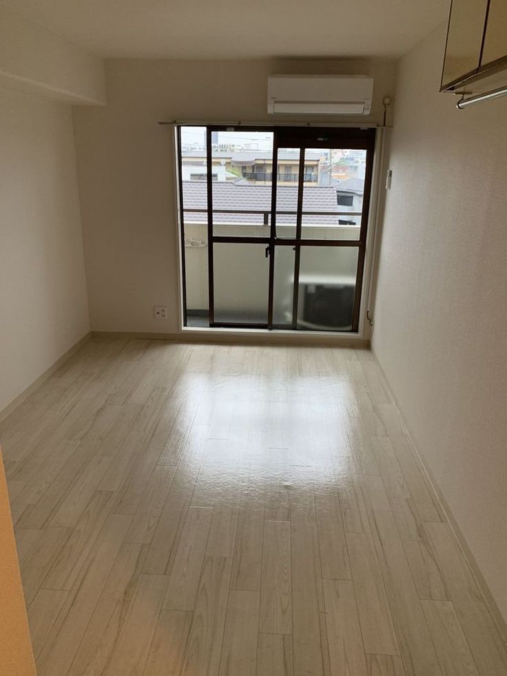 an empty room with hard wood floors and sliding glass doors that lead to the balcony