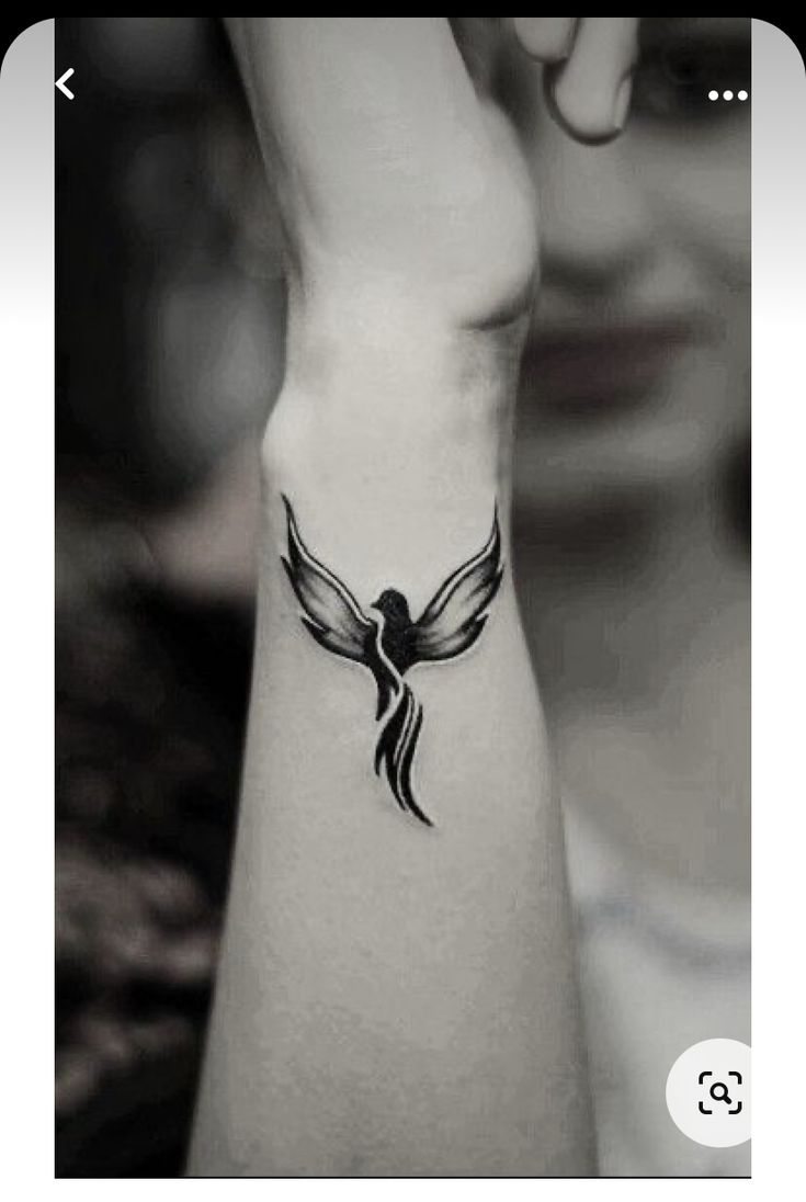 a woman's arm with a bird tattoo on the left side of her wrist