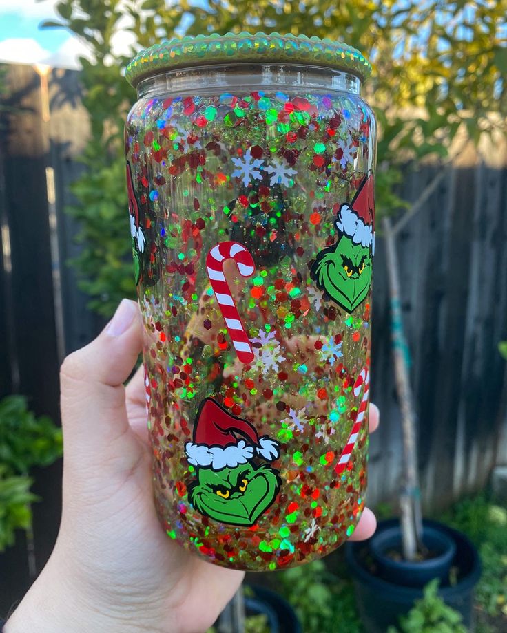 someone holding up a glass with the grin face on it and christmas sprinkles all over it