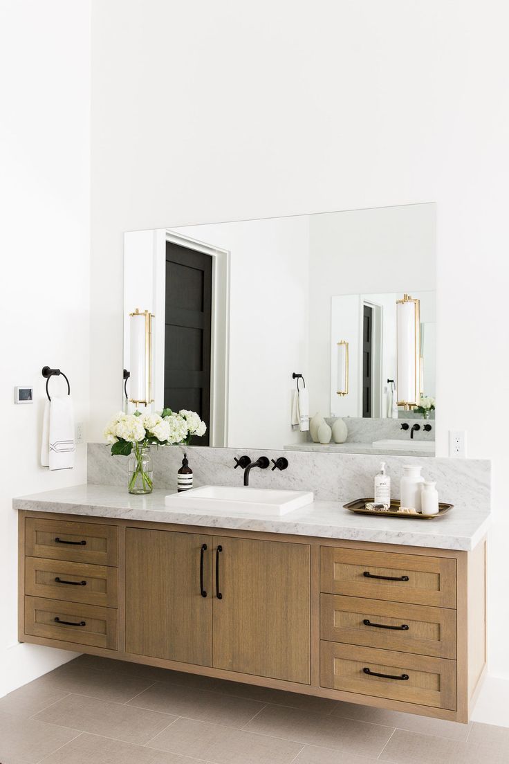 a bathroom vanity with two sinks and large mirror above it, along with other items on the counter