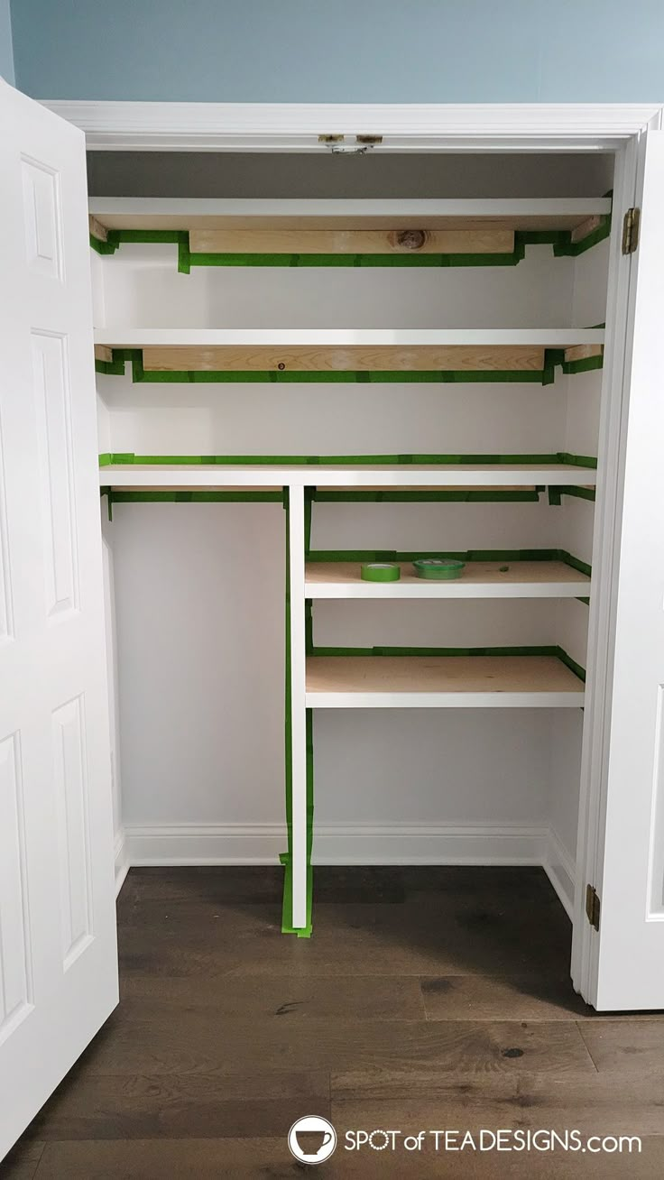 an empty closet with shelves and green tape on the bottom shelf, next to a white door